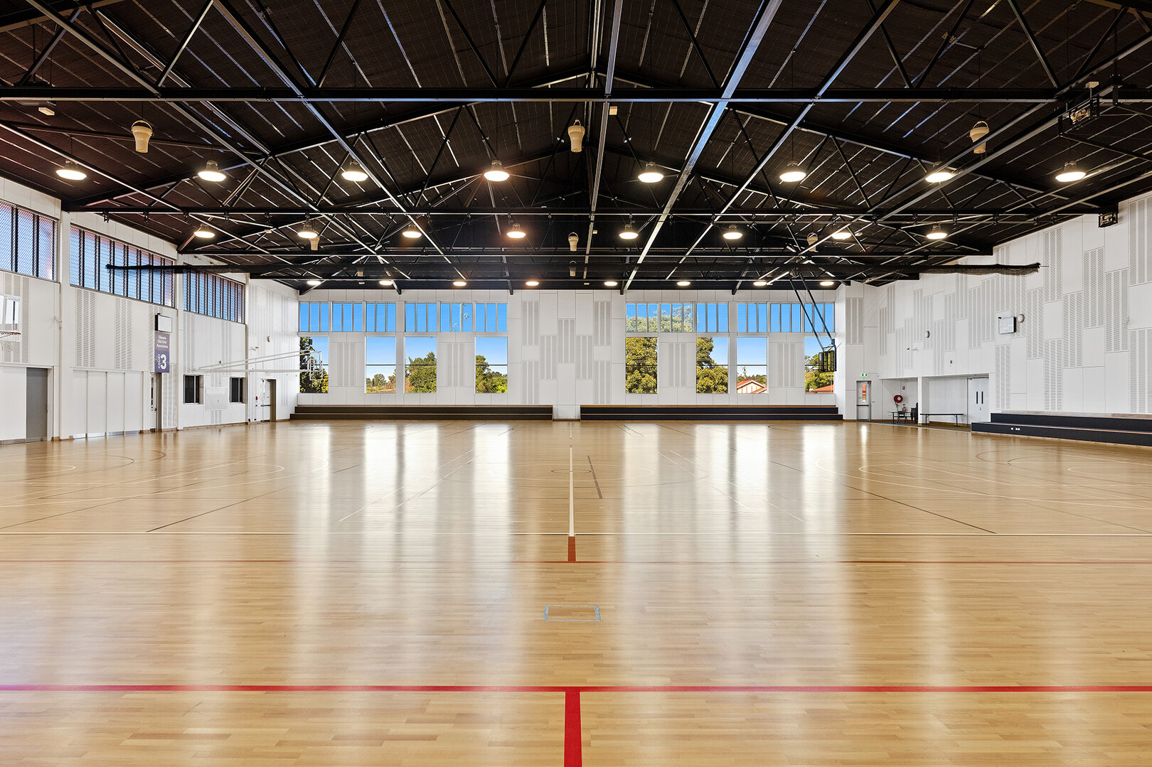 Large indoor sports stadium, brightly lit with overhead lighting and large windows.